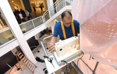 High above the atrium floor, Johnston stitches up the final seam on "Fish Tales." When fully inflated, it is 22 feet high and 18 feet wide. Left: Inside the nylon bag are more than 20 shopping carts weighing 1,800 pounds. Attached to the bag are four vacuums, two that pump air into the bag, two that suck air out. It takes 14 minutes for the bag to fully inflate, then deflate again.