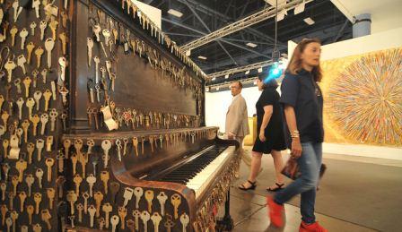 Una mujer pasa al lado de un piano cubierto de llaves, obra de Nari Ward, en el marco de la Feria Art Basel Miami Beach 2015, en esa ciudad floridana. EFE