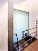 En la vivienda, un gran panel de vidrio esmerilado separa el vestíbulo de la ducha del baño principal