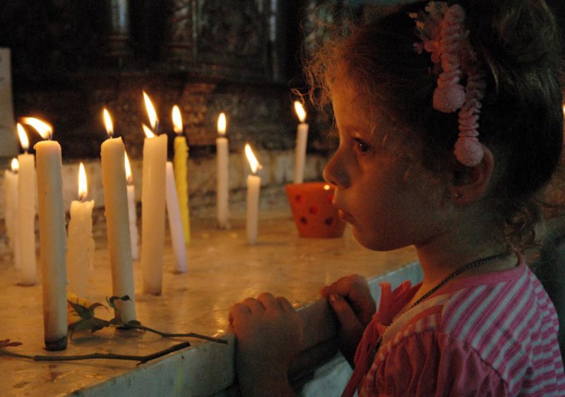 Creyente en santuario de la virgen de la caridad del cobre, le prende velas