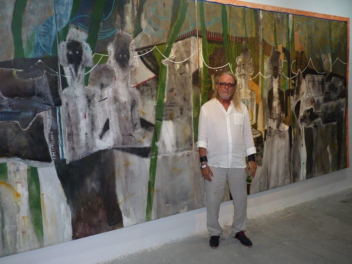 Moisés Finalé, artista plastico promotor del proyecto Sitio en Construcción posa al lado de una de sus obras