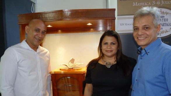 El orfebre Yaniel Rodríguez Benítez,  Lillian Acosta y Angel Miranda, posan al lado del humidor del proyecto Sikerei Art Gallery en el XXI Festival Internacional del Habano