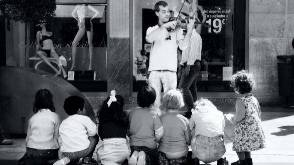 Fotografía callejera. persona toca violín ante niños. Quino Al
